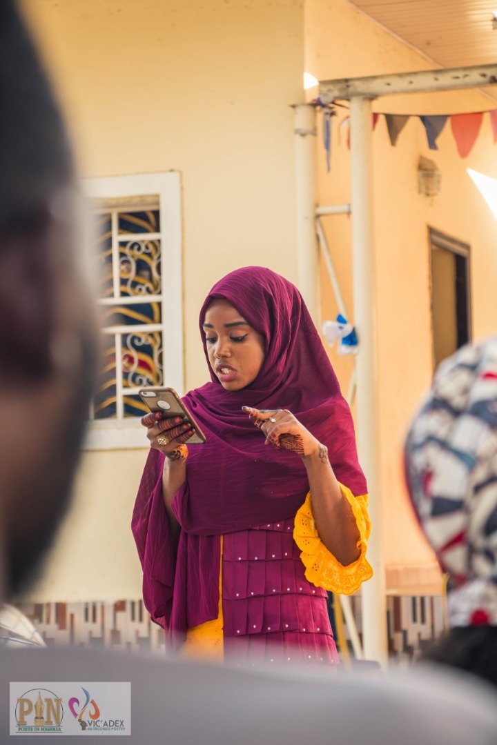 Poet reading from her phone at Open Mic Maiduguri